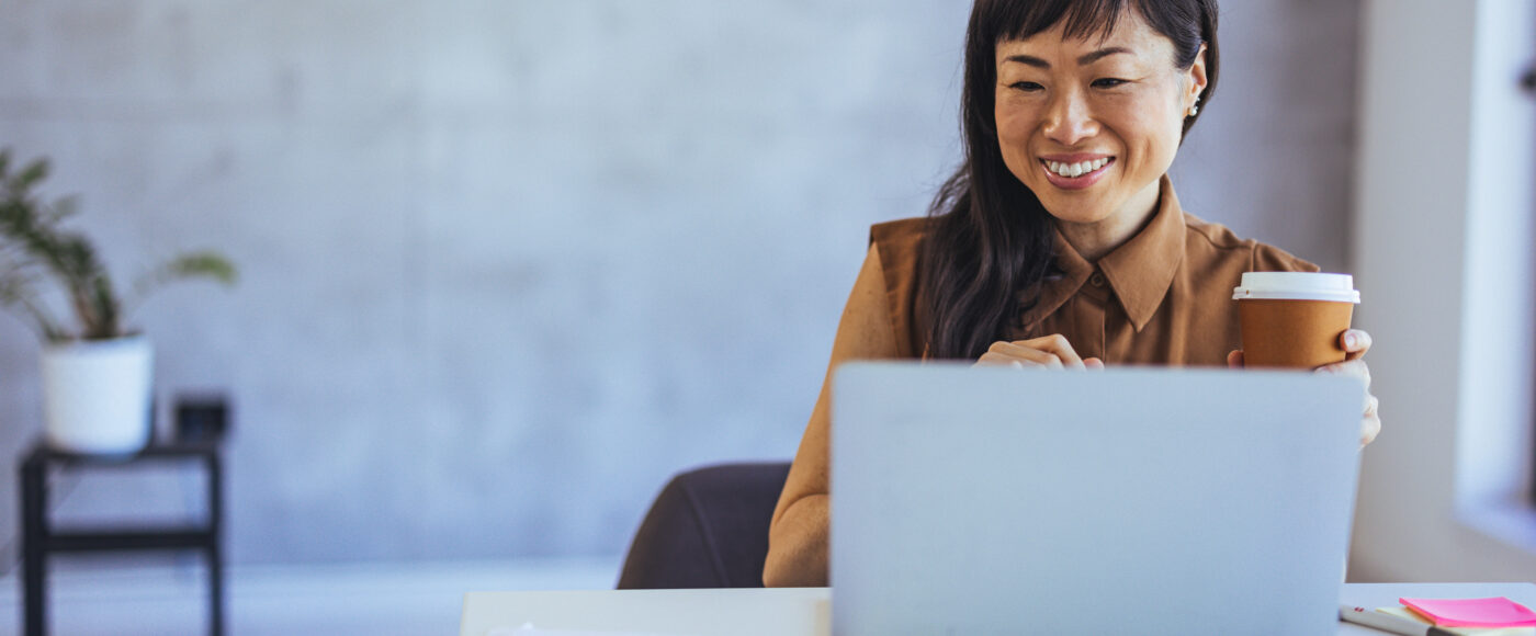 I Stock Venture Capital conference smiling business professional on laptop with coffee in modern office