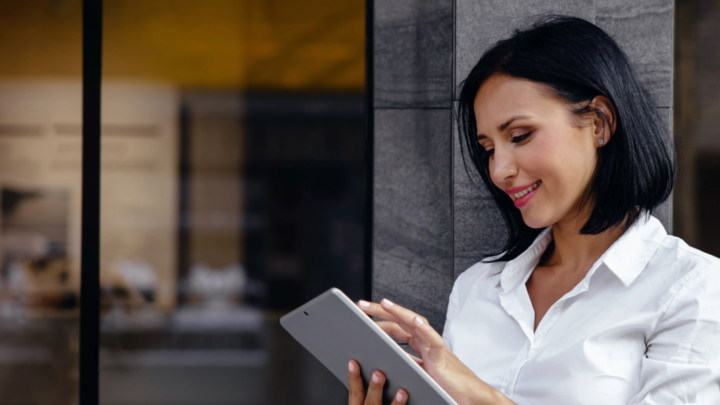 Women in business attire holding tablet outside
