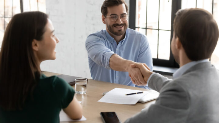 I Stock Business Explorer PLAN Team celebrating successful deal with a handshake in a naturally lit office
