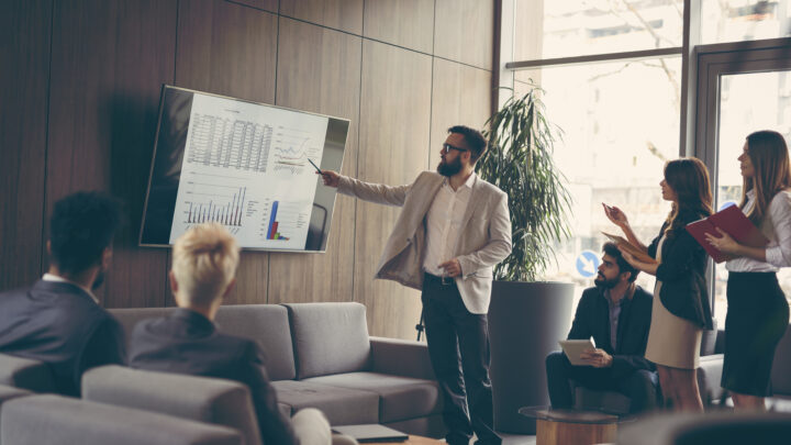 I Stock Innovation boost business person presenting stats on TV in luxury meeting room