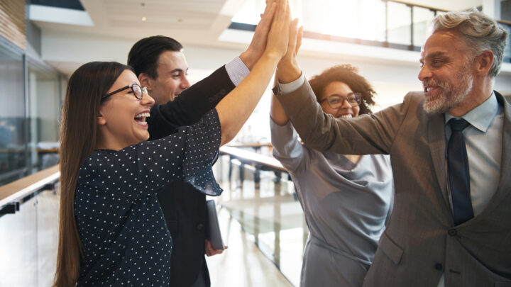 I Stock Synergy business team celebrating in work space by high fiving