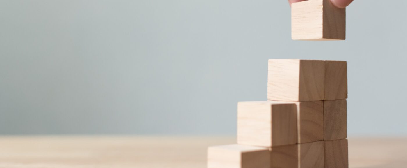 Hand arranging wooden blocks as steps