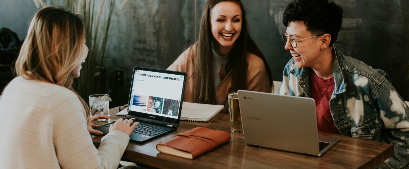 Three people sitting in front of table laughing together