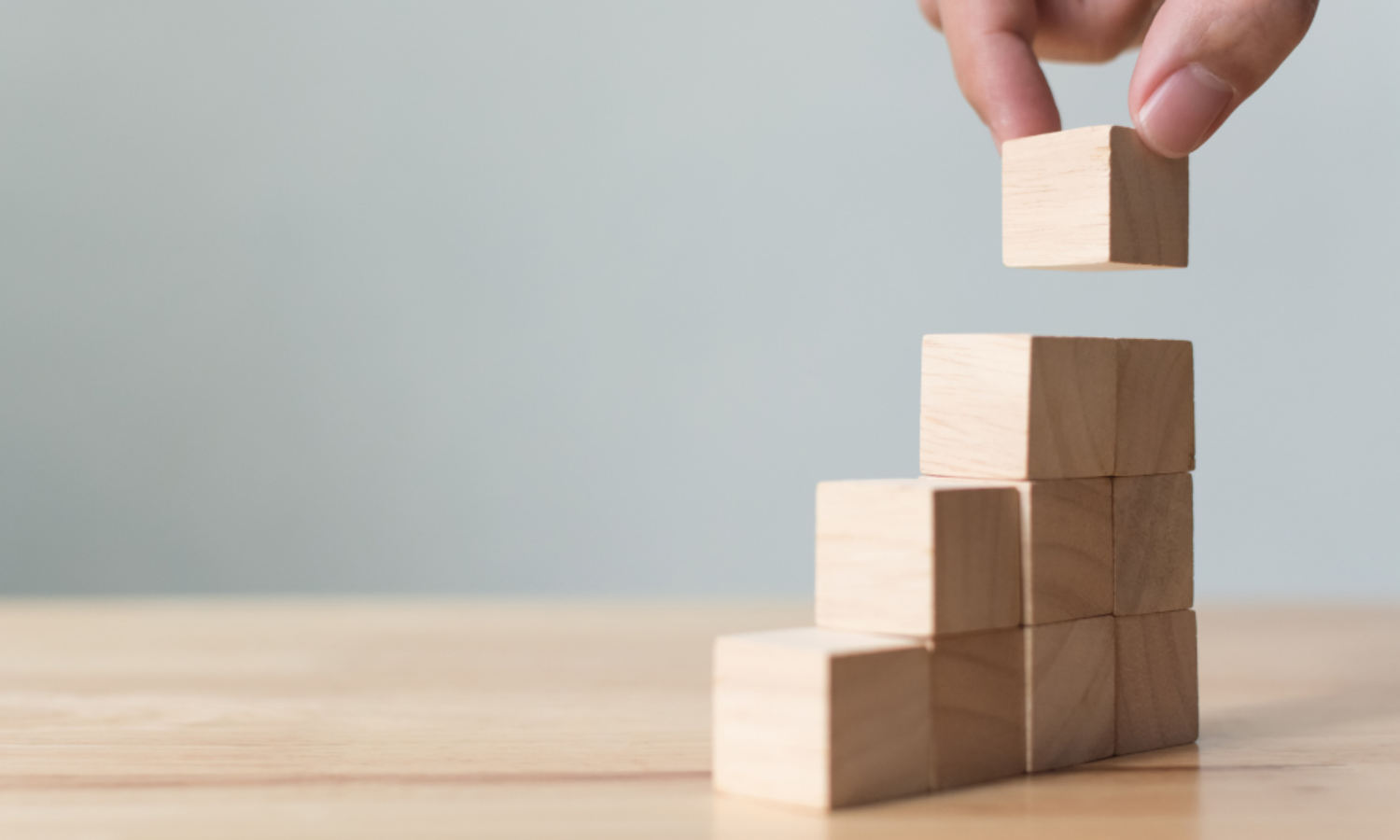 Hand arranging wooden blocks as steps