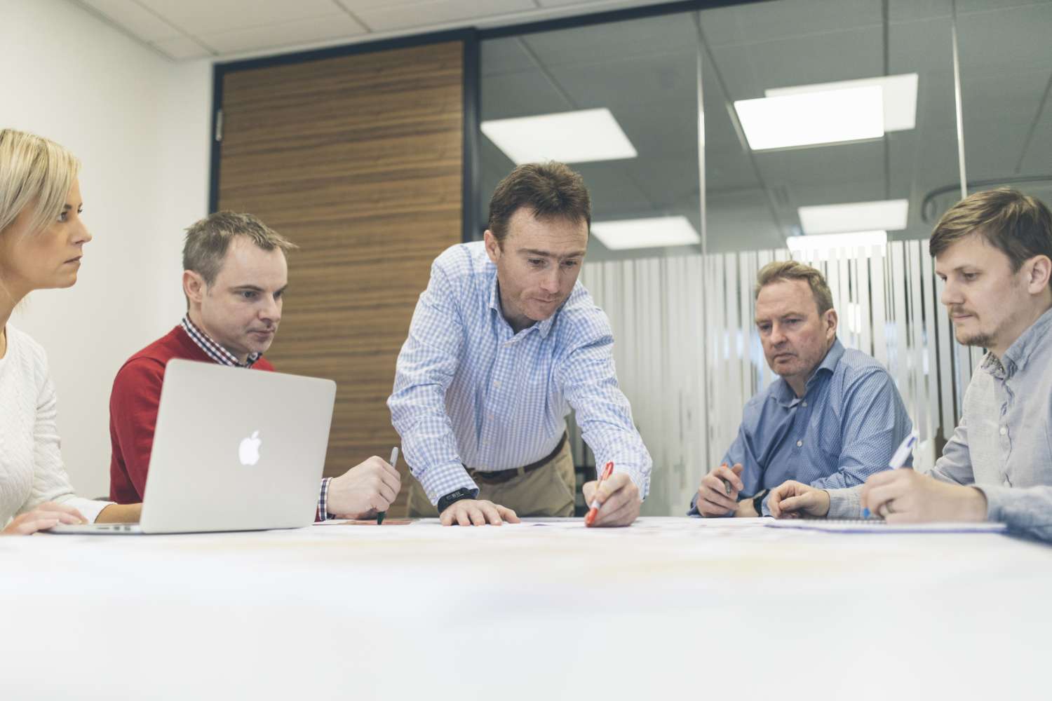 Acumen participants sitting around a meeting table planning using a laptop and pen and paper