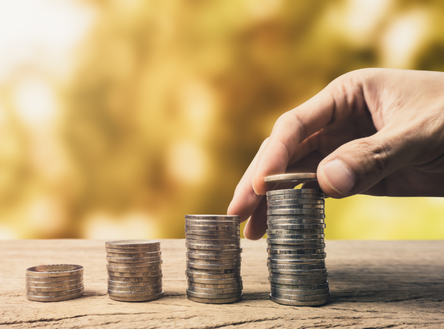 Male hand adding a coin to the top of a stack of coins