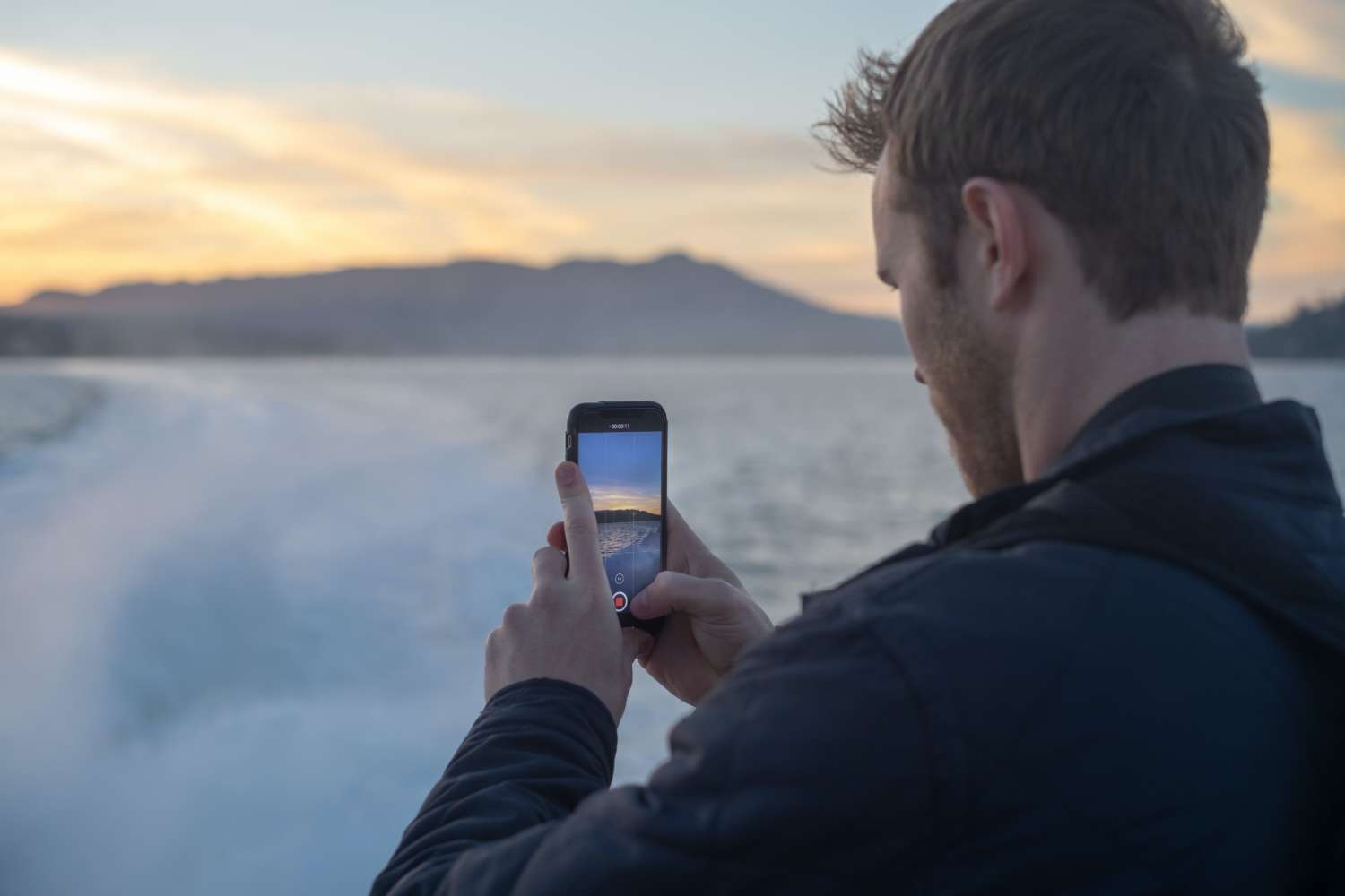 Man taking video of snow covered lake during sunrise
